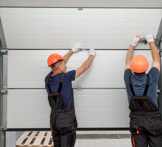 Two contractors performing garage door repair in Davenport IA on a commercial garage door